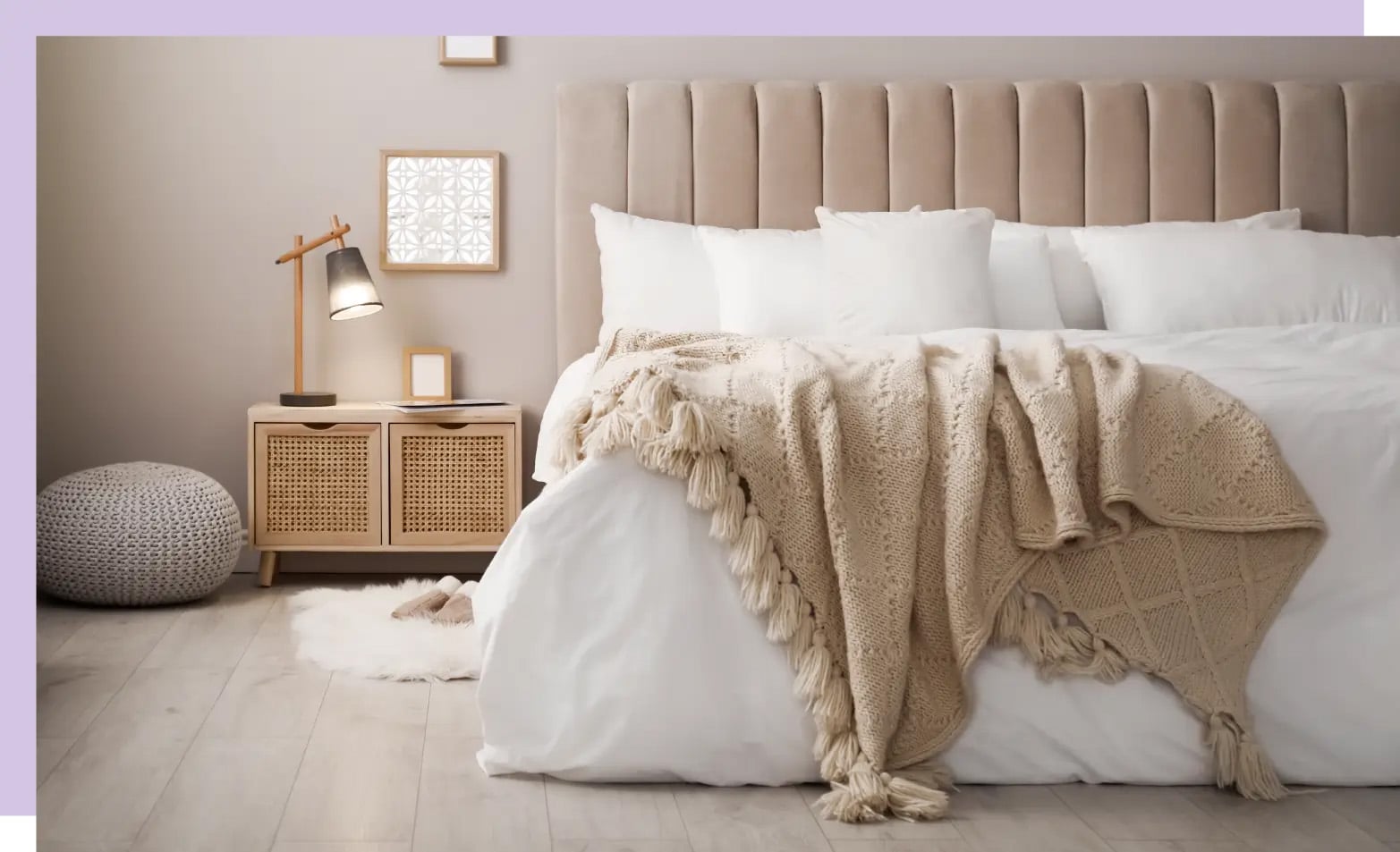A big bed in a room with neutral accents, including a velvet headboard, knit throw blanket, and a wood and cane nightstand.