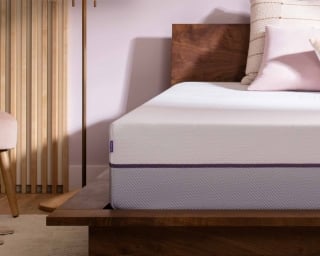 Purple mattress in a dark wood platform bed foundation.