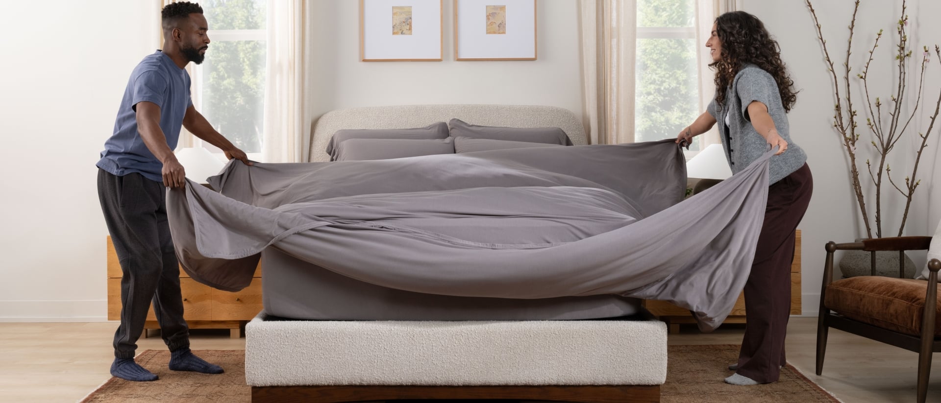 Couple making the bed with SoftStretch sheets